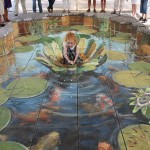 Desenho 3D de Julian Beever com uma criança em cima de seu desenho.